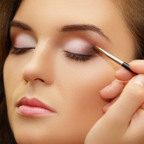 Makeup artist applying cosmetics on model face